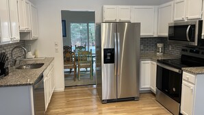 A modern kitchen with stainless steel appliances, white cabinetry, and a wooden floor. - East Hampton SPECIAL (East Hampton)