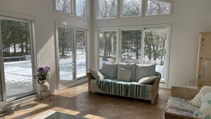 A spacious living room with large windows, a sofa, a coffee table, and a cabinet. - East Hampton SPECIAL (East Hampton)