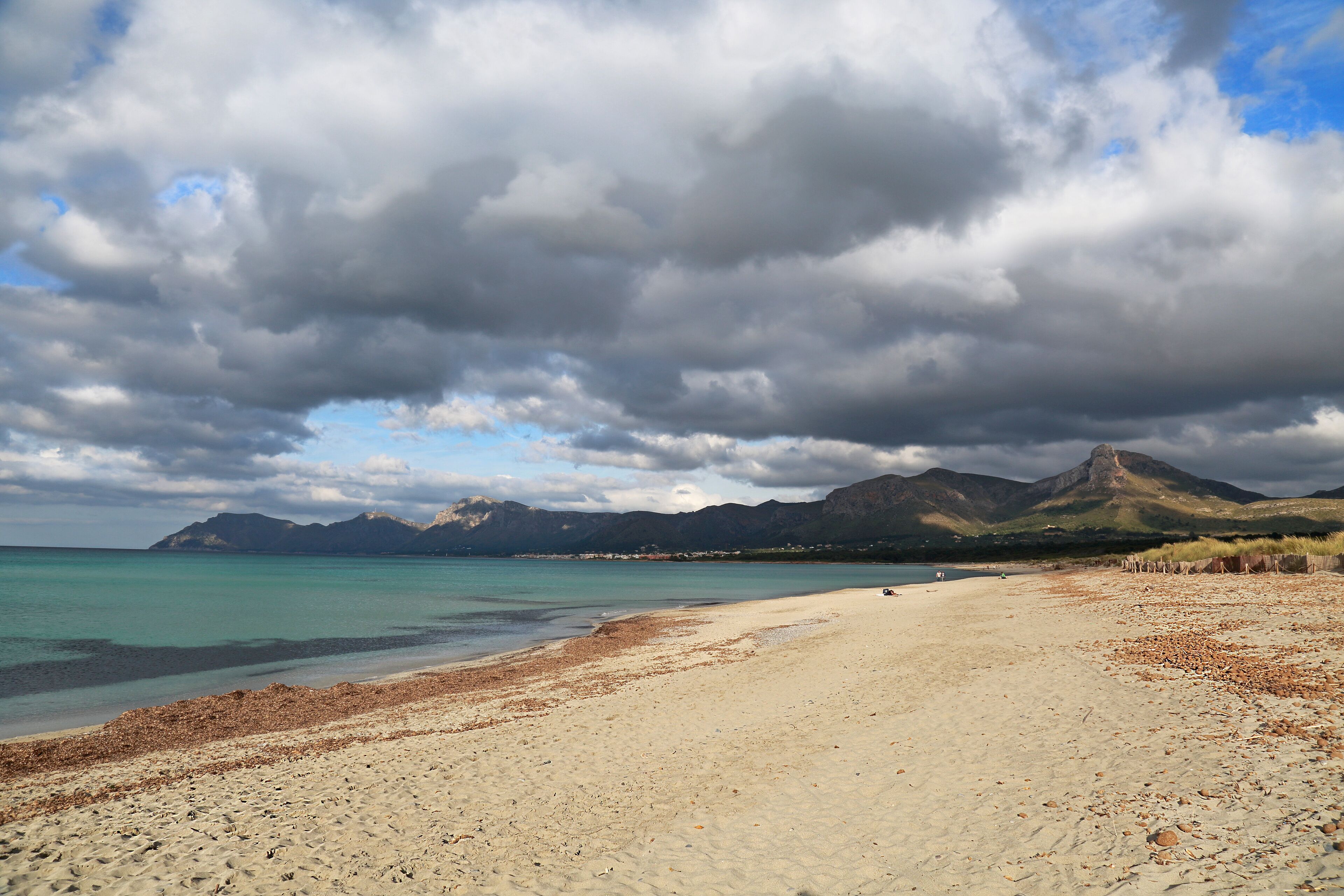 A beach with a clear view of the sea and mountains in the background.