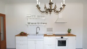 Una cocina con armarios blancos, un lavamanos doble, una estufa y una araña.