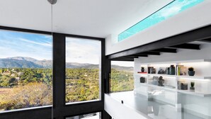 A modern interior with large windows offering a view of a mountainous landscape. - Montblau - Casa de lujo para 8 piscina en la terraza (Buger)