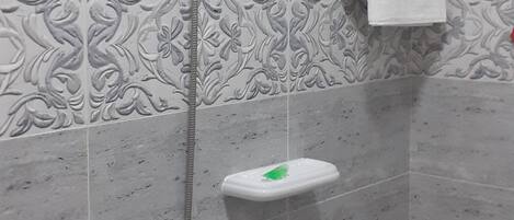 A shower area with a handheld showerhead, a towel rack, and a soap dish.