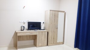 A room with a wooden desk, a computer, a kettle, and a wardrobe. - Dar Al-Jwharah (Duqm)