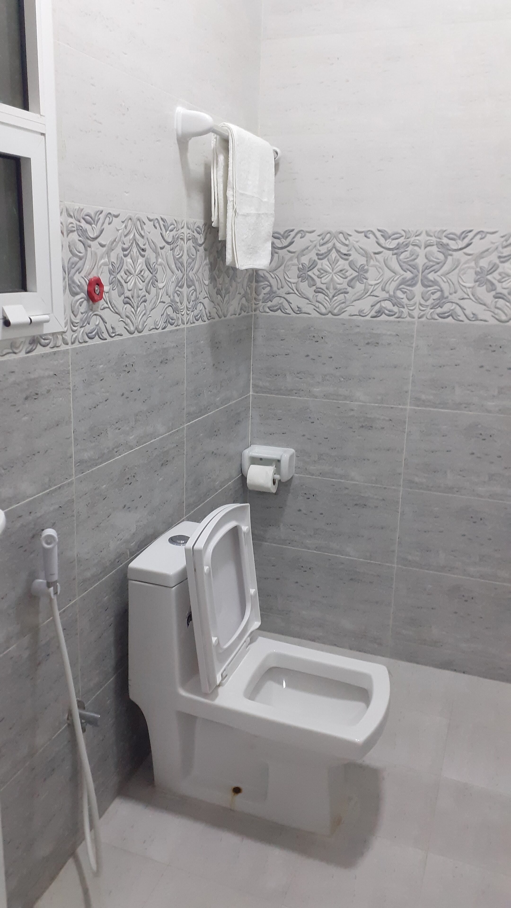 A modern bathroom with a toilet, a hand dryer, and a paper towel dispenser.