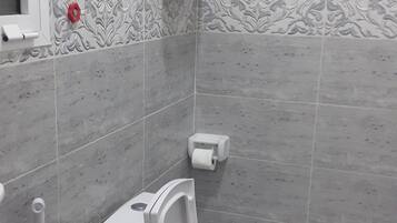 A modern bathroom with a toilet, a hand dryer, and a paper towel dispenser.