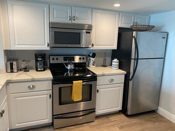 Una cocina moderna con armarios blancos, electrodomésticos de acero inoxidable y un refrigerador negro.