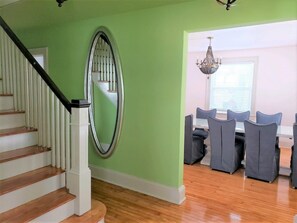 A staircase with white railings and wooden steps leading to a dining area with a chandelier.