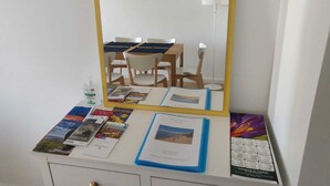 Een kamer met een grote spiegel, een bureau met boeken en een fles, en een stoel.