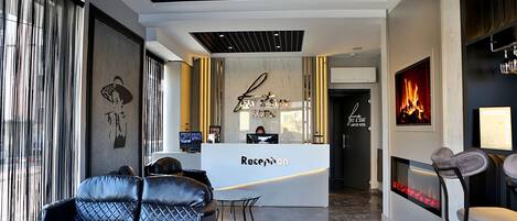 A reception area with a sofa, a reception desk, a fireplace, and a wall with a framed picture.