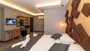 A modern hotel room with a large bed, a TV, a desk, and a mirror. - Fly And Stay Airport Hotel (Arnavutköy)