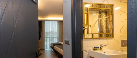 Quarto de hotel com cama, banheiro com um espelho grande e uma porta com a inscrição 405.