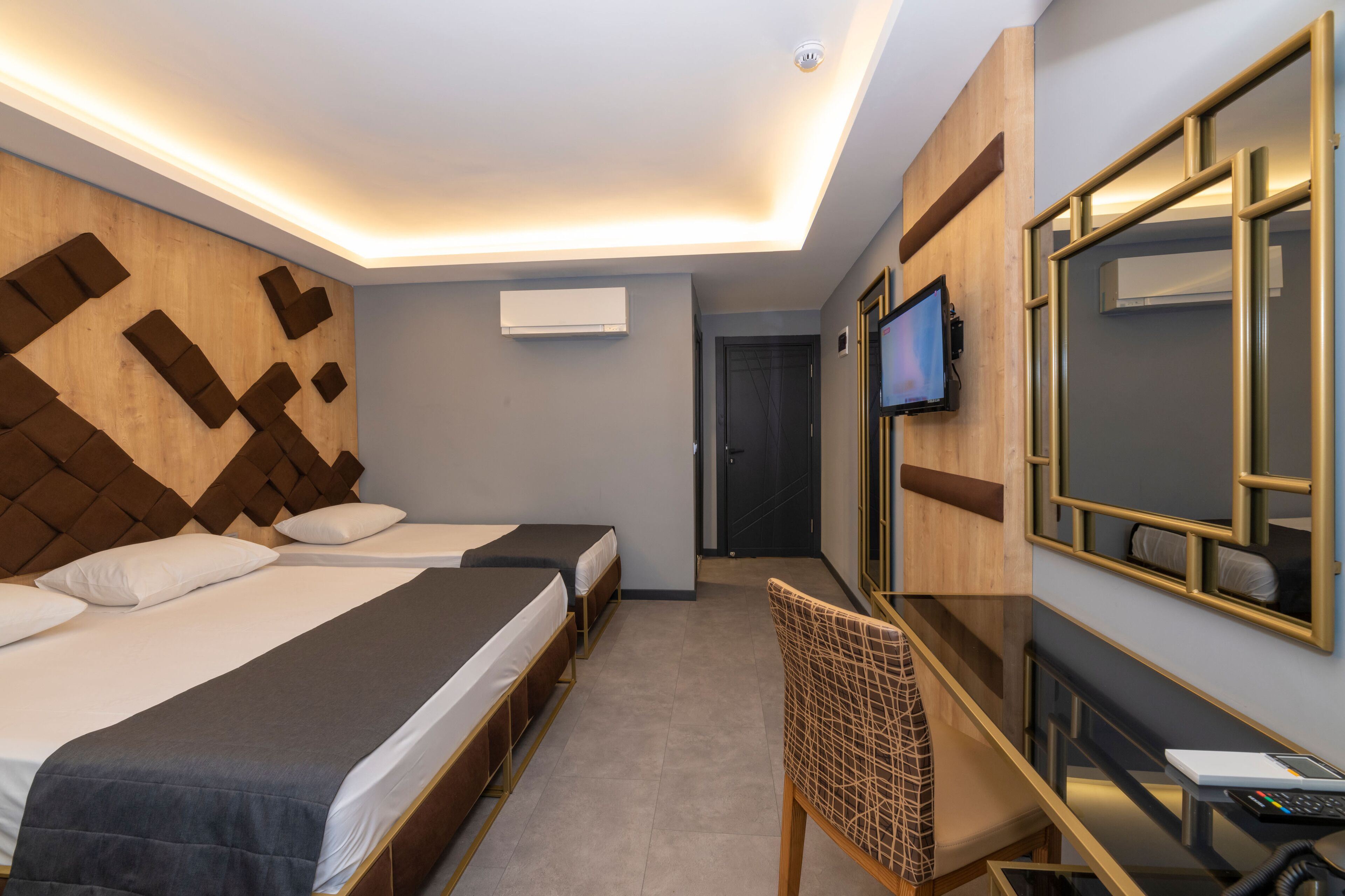 Une chambre d’hôtel avec deux lits, un bureau, une chaise, une télévision et un miroir.