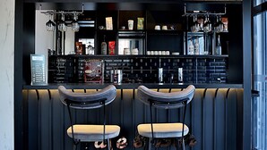 A modern bar area with two stools, a black counter, and various bar equipment. - Fly And Stay Airport Hotel (Arnavutköy)