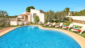 A swimming pool with lounge chairs and a building with a balcony.