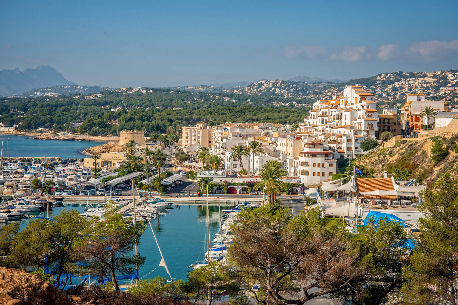 Une ville côtière dotée d’un port de plaisance, de bâtiments à l’architecture méditerranéenne et bordée de montagnes.