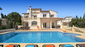 A two-story building with a swimming pool, outdoor seating, and a view of the surrounding area.