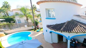 Un espace aménagé au bord de la piscine, avec un patio couvert, une table à manger et une chaise.