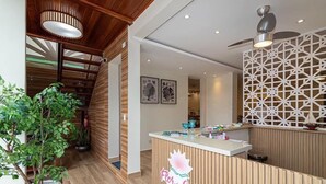 A reception area with a wooden reception desk, a potted plant, and a decorative wall panel. - Pousada Flor de Lótus (Ubatuba)