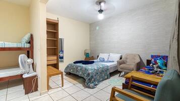 Un dormitorio pequeño con literas, una cama individual, un escritorio y una silla.