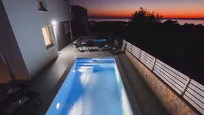 A swimming pool with a sunset view, outdoor seating, and a stone wall. - Funtastic C Apartment with Pool and Terrace (Novalja)