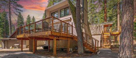 A cabin with a wooden deck, a staircase, and a large window.