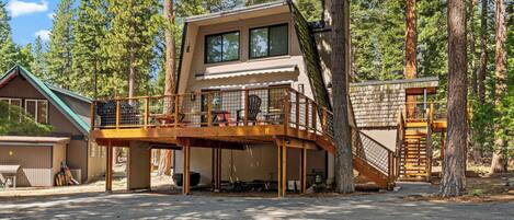 A cabin with a deck, a staircase, and a garage.