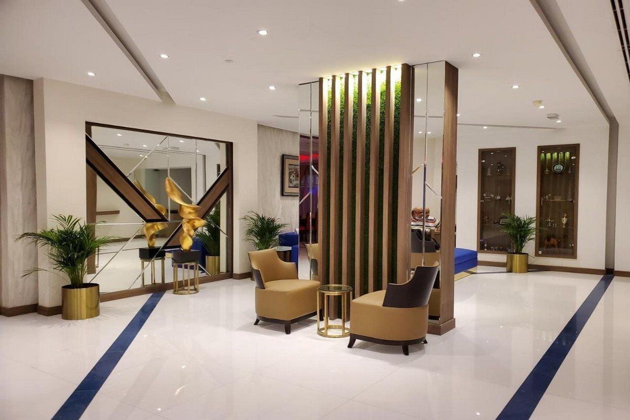 A modern lobby with a glass partition, seating area, and decorative plants.