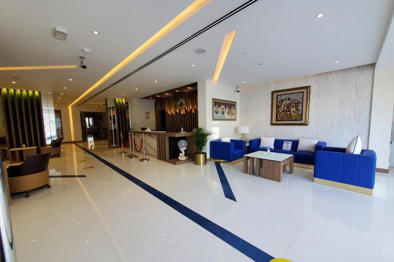 A modern hotel lobby with a reception desk, seating area, and a large painting on the wall.