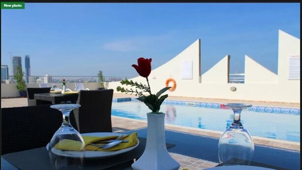 A dining table with a vase of flowers, a glass, and a plate set for two. - Skylark Hotel Apartments (Dubai)