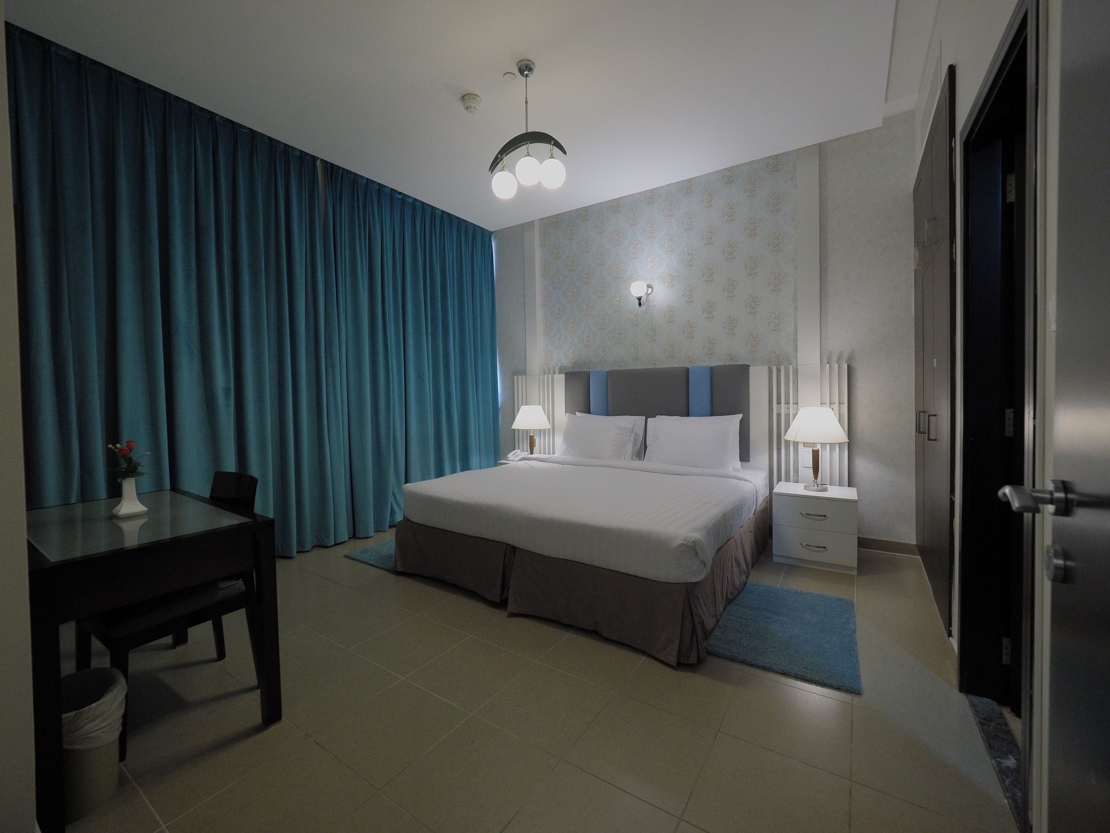 A hotel room with a bed, bedside tables, a desk, and a chair.