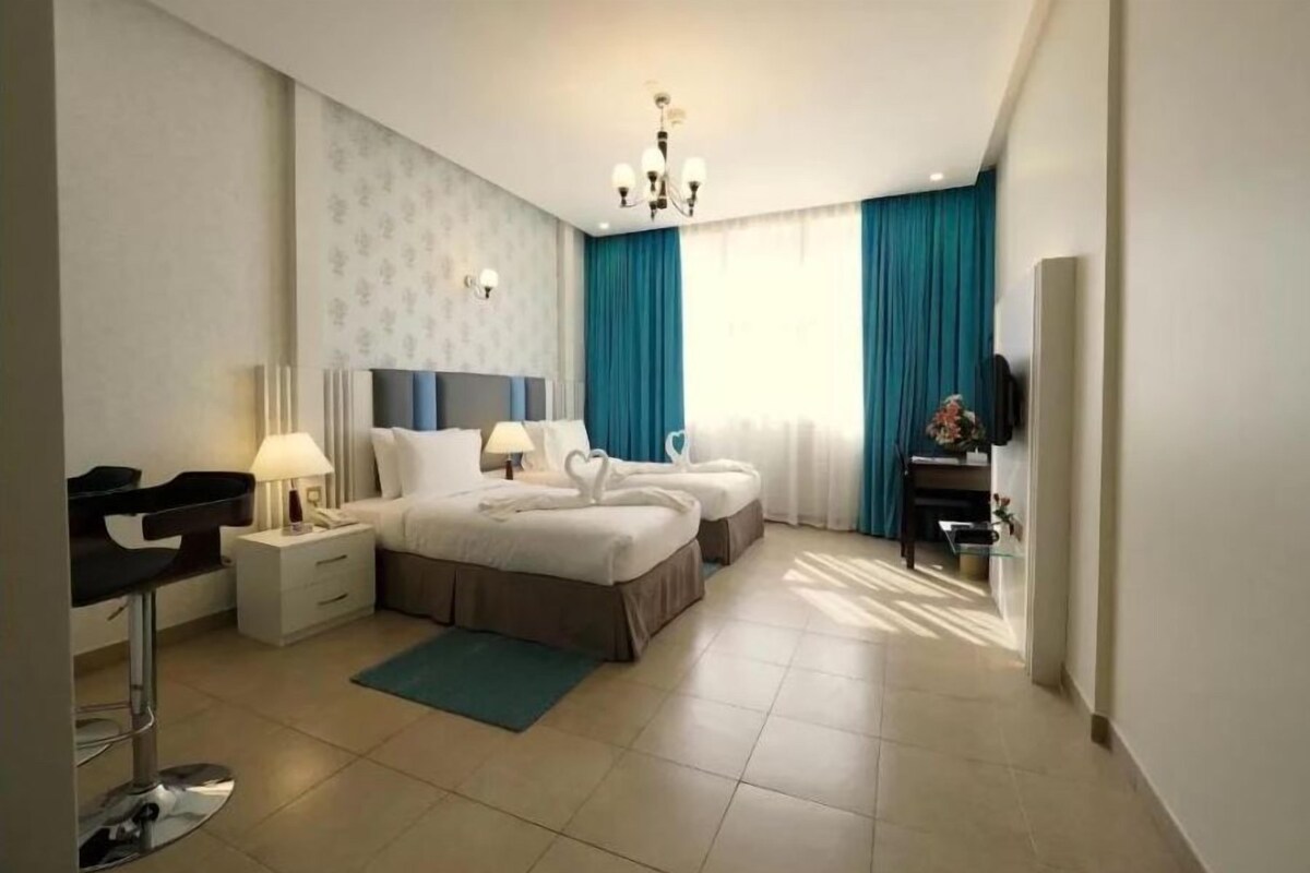 A modern hotel room with a large bed, two bedside tables, a desk, and a chair.
