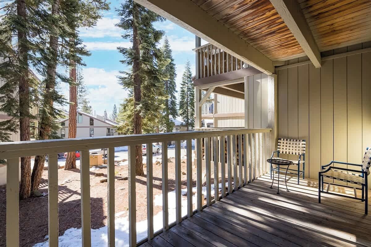 Een houten terras met een balustrade, een bank en een tafel.