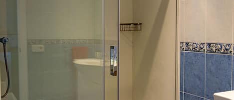 A modern bathroom with a glass-enclosed shower, a toilet, and a sink.