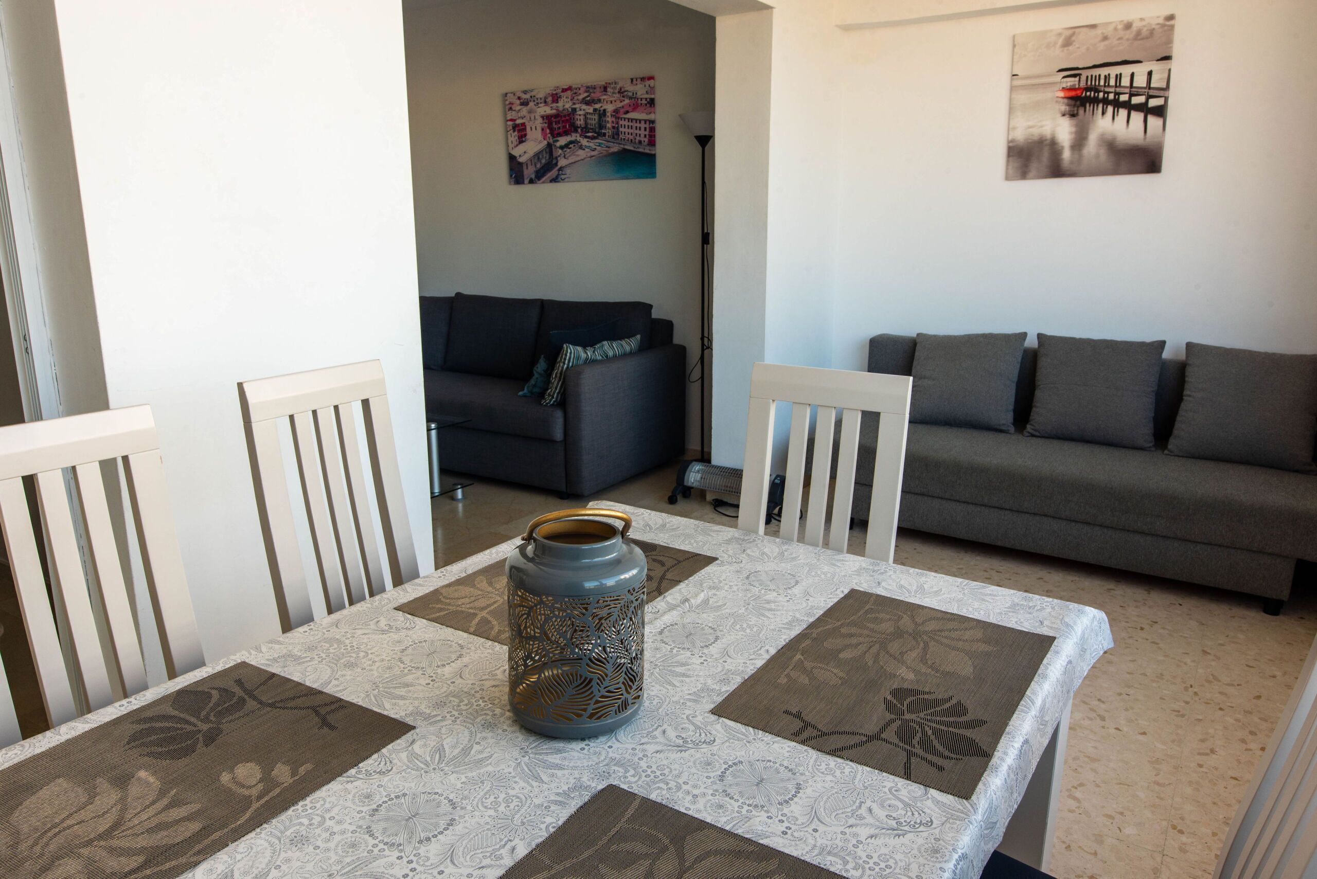 Een woonkamer met een tafel, twee banken en een decoratieve vaas.