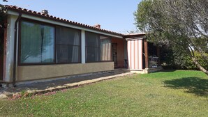 Ein Haus mit großen Fenstern, einer Veranda und einem gepflegten Rasen.