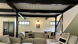 A modern living room with a sectional sofa, a coffee table, and a built-in refrigerator.