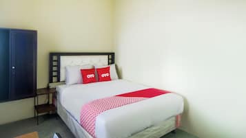 Una habitación de hotel con una cama, una mesita de noche, un armario y una colcha de rayas rojas y blancas.