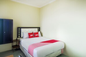 Una habitación de hotel con una cama, una mesita de noche, un armario y una colcha de rayas rojas y blancas.