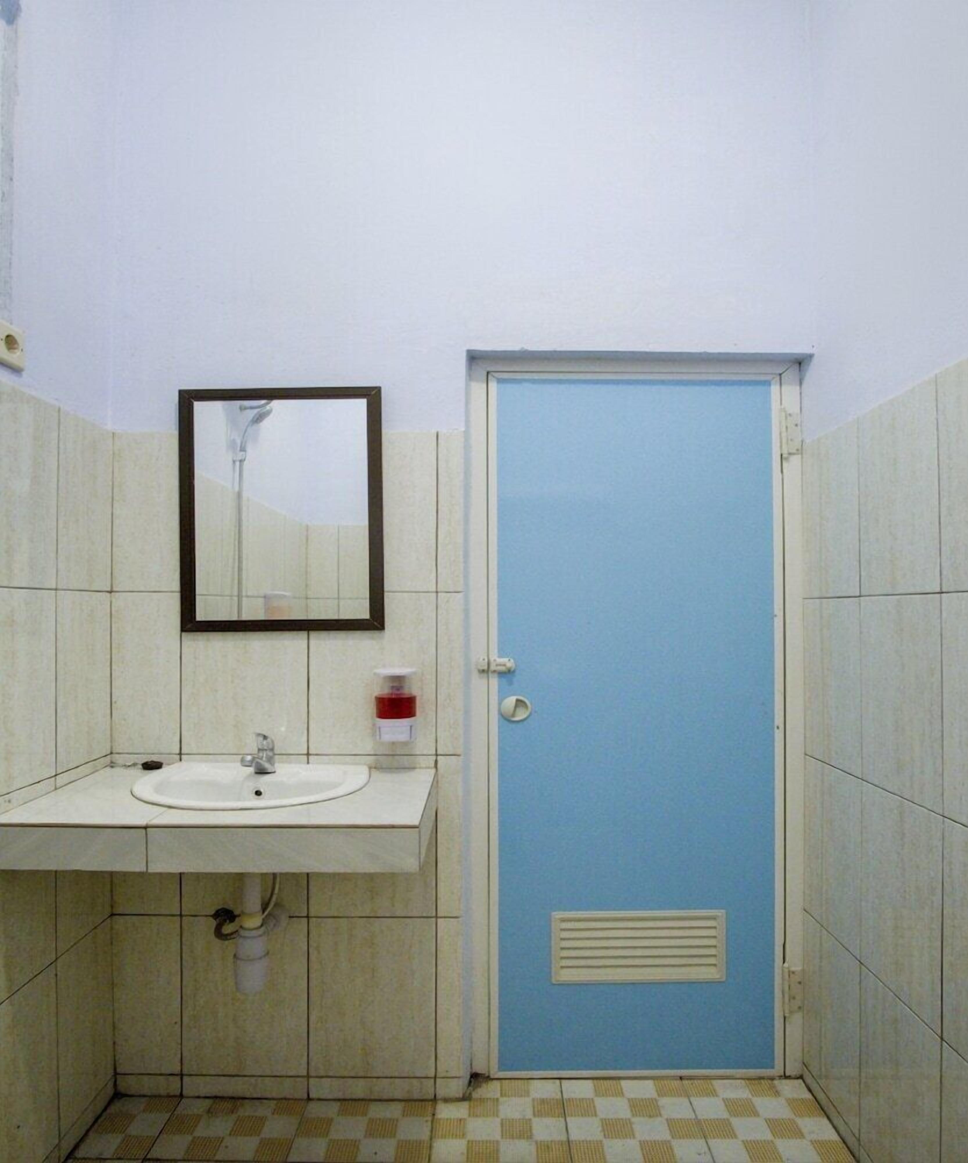 A small bathroom with a sink, mirror, and a blue door.