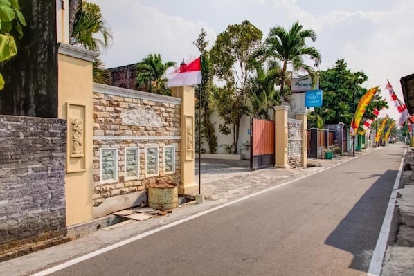 A street lined with buildings, some with flags, and a stone wall with framed pictures.