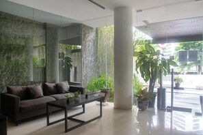 A modern lobby with a sofa, coffee table, and potted plants. - OYO 3931 Wtc Kuningan (Jakarta)