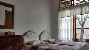 Une chambre à coucher avec un lit double, une commode en bois et un grand miroir.