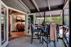 A covered outdoor seating area with wicker furniture and a wooden table.