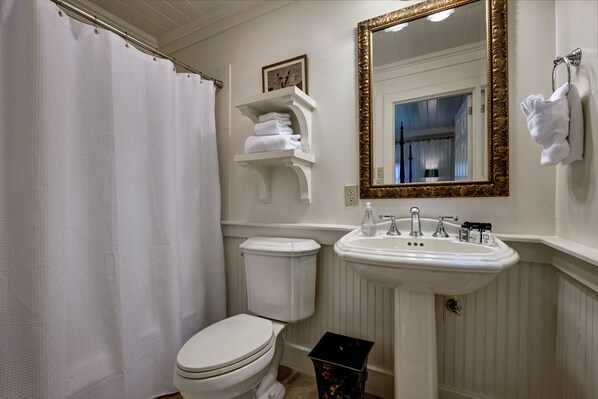 A bathroom with a toilet, sink, and a mirror with a gold frame.