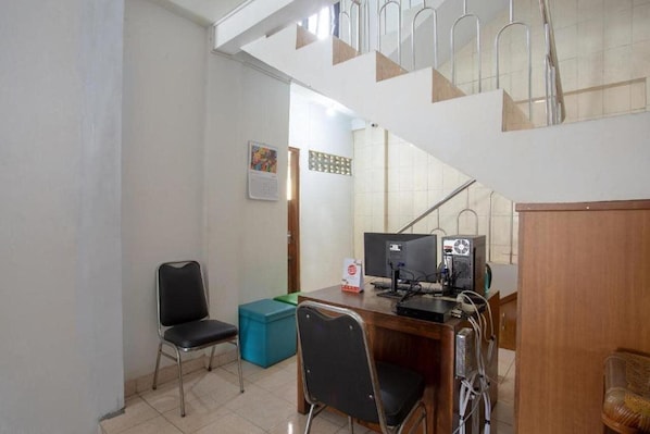 Een kamer met een bureau, twee stoelen, een computer en een trap.