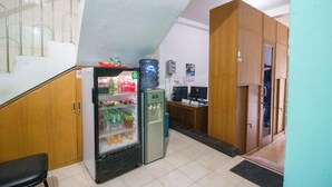 Eine kleine Küchenzeile mit Kühlschrank, Wasserspender und Spüle. Es ist ein Holzschrank und eine Bank vorhanden.