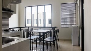 A modern kitchen with a dining area, large windows, and a built-in air conditioner. - OYO 3251 D'daun Inn (Karawang)