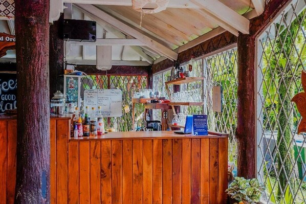A wooden bar area with a chalkboard menu, various bottles, and a signboard. - OYO 3889 D'ratna Resort (Cugenang)