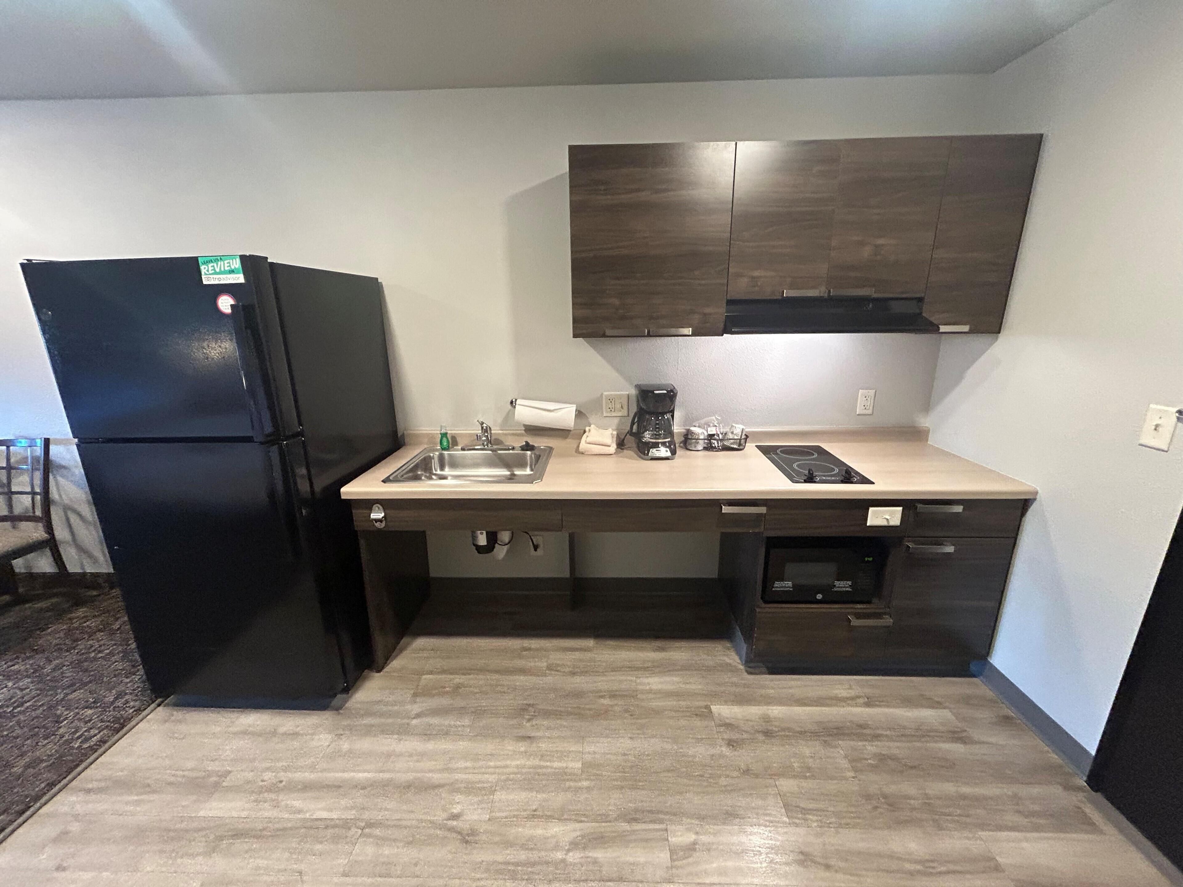 A compact kitchen with a refrigerator, sink, coffee maker, and built-in microwave.