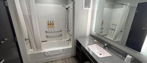 A modern bathroom with a bathtub, shower, vanity, and a large mirror.